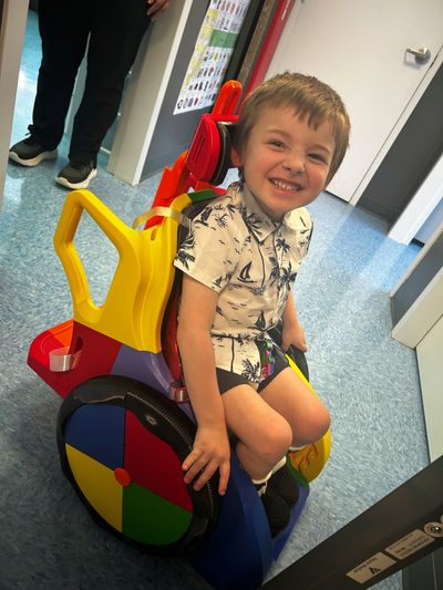Boy is shown in red and yellow Toddler Mobility Trainer
